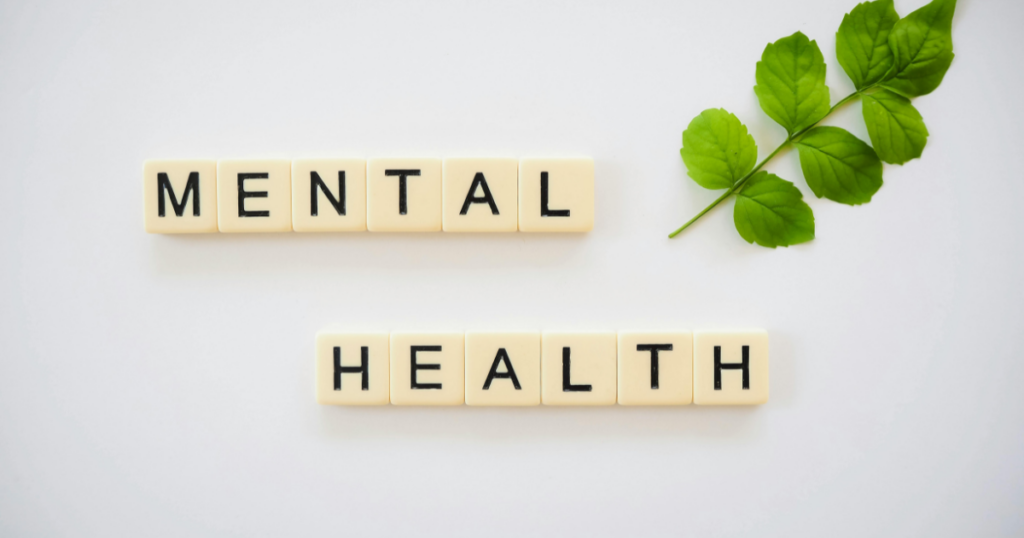 image - Mental Health Center Of San Diego Tiles spell out 'MENTAL HEALTH' with a green leafy sprig in the top-right corner on a white background, conveying the concept of mental health.