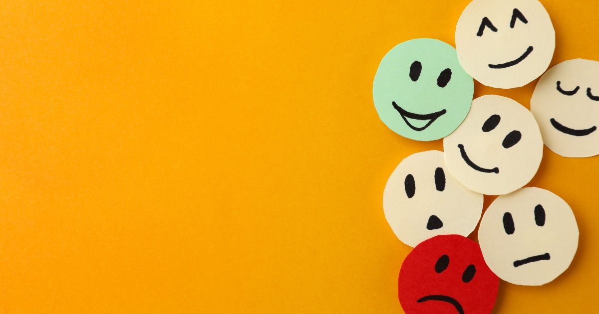 Group of round sticky notes with various facial expressions (happy, sad, neutral) on an orange background.